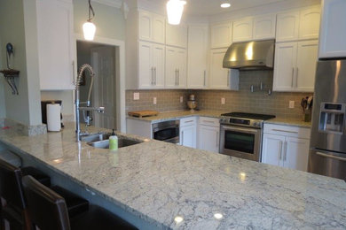 Example of a mid-sized transitional dark wood floor and brown floor open concept kitchen design in San Diego with a double-bowl sink, recessed-panel cabinets, white cabinets, granite countertops, subway tile backsplash, stainless steel appliances, a peninsula and gray backsplash