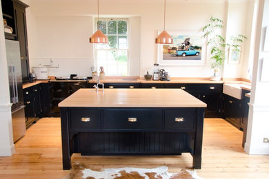 This is an example of a scandinavian u-shaped open plan kitchen in Other with a double-bowl sink, shaker cabinets, blue cabinets, wood benchtops, stainless steel appliances and with island.