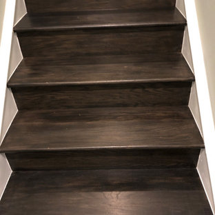 Large modern look-out basement with black walls, vinyl flooring, no fireplace and brown floors.