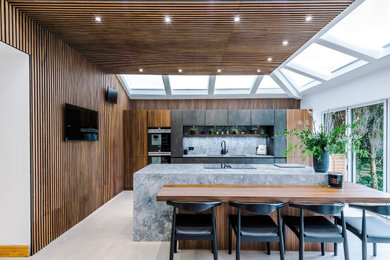 Inspiration for a large contemporary open plan kitchen in Manchester with an integrated sink, medium wood cabinets, quartz worktops, stainless steel appliances, multiple islands, a wood ceiling and a feature wall.