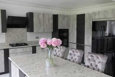 Moderne Küche mit Granit-Arbeitsplatte, schwarzen Elektrogeräten und Kücheninsel in Essex