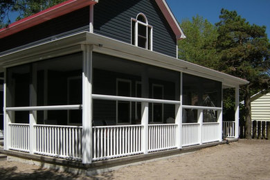 This is an example of a mid-sized traditional concrete screened-in back porch design in Toronto with a roof extension.