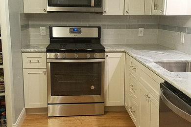 Inspiration for a small coastal l-shaped light wood floor eat-in kitchen remodel in Cleveland with an undermount sink, shaker cabinets, white cabinets, quartzite countertops, gray backsplash, glass tile backsplash, stainless steel appliances, no island and blue countertops