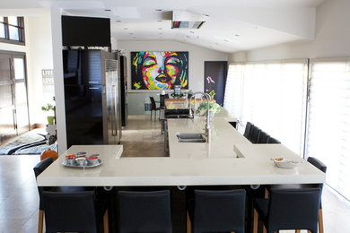 Large minimalist galley porcelain tile and beige floor open concept kitchen photo in Edmonton with a double-bowl sink, flat-panel cabinets, black cabinets, quartz countertops, stainless steel appliances and no island
