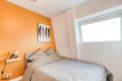 Foto de dormitorio contemporáneo con parades naranjas y suelo de madera clara