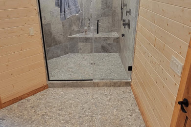 Mid-sized stone tile pebble tile floor and wall paneling doorless shower photo in Minneapolis with a bidet, brown walls and a hinged shower door