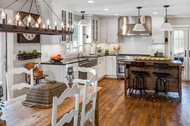 Cottage l-shaped dark wood floor kitchen photo in Minneapolis with a farmhouse sink, shaker cabinets, white cabinets, white backsplash, subway tile backsplash, stainless steel appliances and an island
