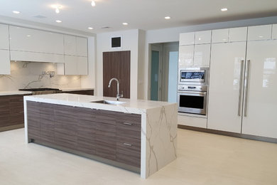 Example of a large trendy kitchen design in San Diego with flat-panel cabinets, white cabinets, marble countertops, white backsplash, stone slab backsplash, stainless steel appliances, an island and an undermount sink