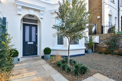 Photo of a mid-sized contemporary three-storey stucco white exterior in London with a flat roof.