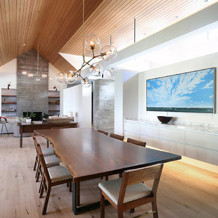 Cette photo montre une salle à manger ouverte sur le salon tendance de taille moyenne avec un mur blanc, un sol en bois brun, un sol marron, une cheminée standard et un manteau de cheminée en bois.