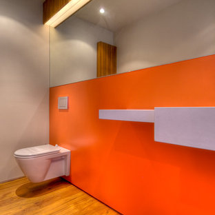 Esempio di una stanza da bagno moderna con lavabo sospeso, WC sospeso e pareti arancioni