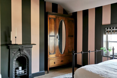 他の地域にある中くらいな北欧スタイルのおしゃれな客用寝室 (マルチカラーの壁、淡色無垢フローリング、標準型暖炉、金属の暖炉まわり、ベージュの床、壁紙)