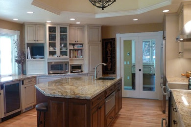 Inspiration for a mid-sized timeless u-shaped light wood floor enclosed kitchen remodel in Seattle with an undermount sink, raised-panel cabinets, light wood cabinets, granite countertops, beige backsplash, glass tile backsplash, stainless steel appliances and an island