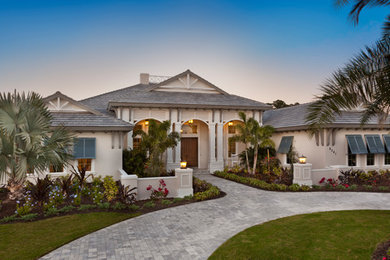 Design ideas for an expansive tropical one-storey stucco beige house exterior in Tampa with a shingle roof.