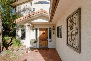 Elegant porcelain tile and red floor entryway photo in Austin with beige walls and a medium wood front door