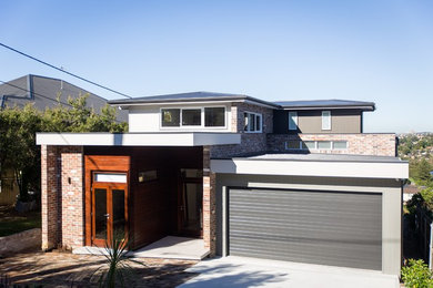 Photo of a large contemporary three-storey brick house exterior in Sydney with a flat roof and a metal roof.