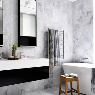 Freestanding bathtub - contemporary white tile freestanding bathtub idea in New York with flat-panel cabinets, black cabinets and an integrated sink