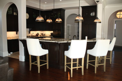 Example of a classic ceramic tile kitchen design in Orlando with an undermount sink, flat-panel cabinets, dark wood cabinets, granite countertops, white backsplash, subway tile backsplash, paneled appliances and an island