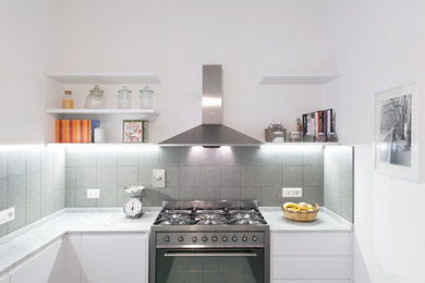 Photo of a small contemporary l-shaped kitchen in Rome with flat-panel cabinets, white cabinets, marble benchtops, grey splashback, ceramic splashback, stainless steel appliances and ceramic floors.