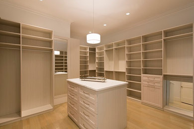 Example of a large beach style gender-neutral light wood floor walk-in closet design with shaker cabinets and light wood cabinets