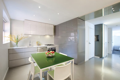Photo of a contemporary eat-in kitchen in Melbourne with an undermount sink, grey cabinets, quartz benchtops, green splashback, glass sheet splashback, stainless steel appliances, concrete floors and no island.