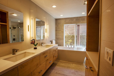 This is an example of a large contemporary master bathroom in Sacramento with flat-panel cabinets, light wood cabinets, a freestanding tub, a corner shower, a wall-mount toilet, beige tile, porcelain tile, beige walls, porcelain floors, an undermount sink, engineered quartz benchtops, beige floor and white benchtops.