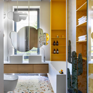Cette photo montre une salle de bain tendance avec un placard à porte plane, des portes de placard en bois brun, une baignoire d'angle, un mur blanc, sol en terrazzo, une vasque, un sol multicolore et un plan de toilette blanc.