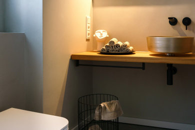 Kleine Stilmix Gästetoilette mit Wandtoilette mit Spülkasten, grauen Fliesen, grauer Wandfarbe, Marmorboden, Aufsatzwaschbecken, Waschtisch aus Holz, grauem Boden und schwebendem Waschtisch in Dortmund
