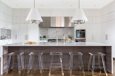 Enclosed kitchen - large contemporary u-shaped light wood floor and brown floor enclosed kitchen idea in Chicago with an undermount sink, flat-panel cabinets, white cabinets, quartzite countertops, white backsplash, stainless steel appliances, an island, white countertops and stone slab backsplash