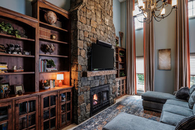 Example of a large transitional ceramic tile family room design in Other with blue walls, a stone fireplace and a wall-mounted tv