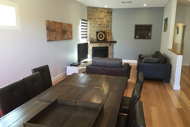 Large traditional open concept family room in Sydney with grey walls, medium hardwood floors, a corner fireplace, a stone fireplace surround and a freestanding tv.