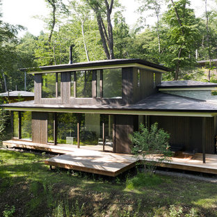 他の地域のモダンスタイルのおしゃれな二階建ての家 (木材サイディング、黒い外壁、寄棟屋根、戸建、金属屋根) の写真