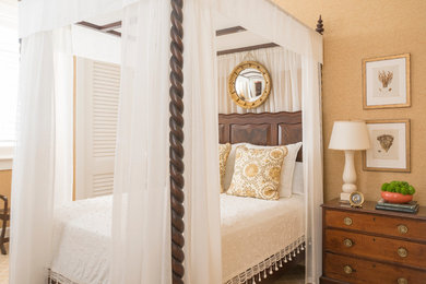 This is an example of a large beach style guest bedroom in Miami with beige walls and light hardwood floors.
