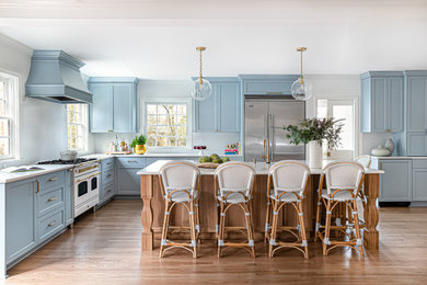 Inspiration for a large timeless l-shaped light wood floor eat-in kitchen remodel in Charlotte with a farmhouse sink, shaker cabinets, blue cabinets, quartz countertops, white backsplash, quartz backsplash, an island and white countertops