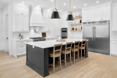 Eat-in kitchen - large contemporary l-shaped light wood floor and brown floor eat-in kitchen idea in Edmonton with shaker cabinets, white cabinets, granite countertops, white backsplash, brick backsplash, an island, white countertops, an undermount sink and stainless steel appliances