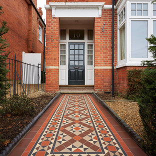 Idéer för eklektiska ingångspartier, med röda väggar, en enkeldörr, en svart dörr och rött golv