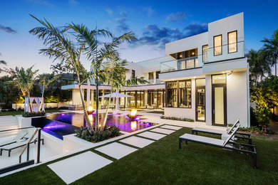 Large modern backyard rectangular infinity pool in Miami with a hot tub and tile.