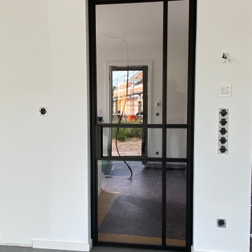 Lofttüren für nahtlose Übergänge: Küche, Flur und Wohnzimmer stilvoll verbunden.