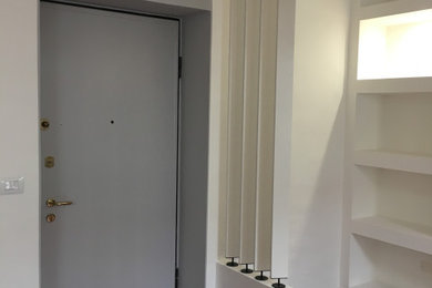 Ispirazione per una piccola porta d'ingresso contemporanea con pareti bianche, pavimento in terracotta, una porta singola, una porta grigia e pavimento rosso