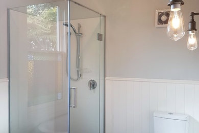 Photo of a mid-sized traditional master bathroom in Christchurch with furniture-like cabinets, medium wood cabinets, a corner tub, a corner shower, black and white tile, multi-coloured walls, a vessel sink and wood benchtops.