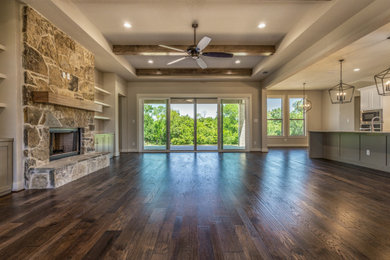 Living room - large traditional formal and open concept medium tone wood floor and exposed beam living room idea in Dallas with beige walls, a standard fireplace, a stone fireplace and a wall-mounted tv