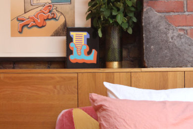 Photo of a large eclectic master bedroom in London with beige walls, carpet, brick walls and a chimney breast.