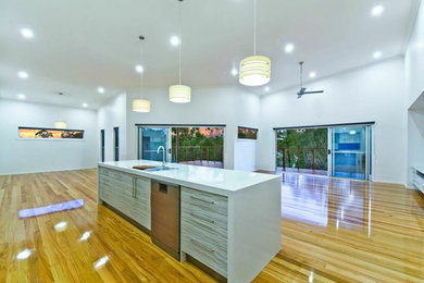 Modern galley eat-in kitchen in Brisbane with a double-bowl sink, beaded inset cabinets, light wood cabinets, granite benchtops, stainless steel appliances, light hardwood floors and with island.