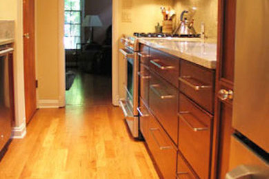 This is an example of a kitchen in Indianapolis with medium wood cabinets, stainless steel appliances and light hardwood floors.
