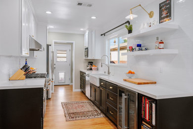 This is an example of a mid-sized contemporary galley eat-in kitchen in Los Angeles with a farmhouse sink, shaker cabinets, quartz benchtops, white splashback, subway tile splashback, stainless steel appliances and white benchtop.