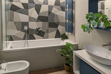 Ispirazione per una stanza da bagno padronale design di medie dimensioni con ante lisce, ante blu, vasca da incasso, vasca/doccia, piastrelle beige, piastrelle in gres porcellanato, pareti beige, parquet chiaro, un lavabo, mobile bagno sospeso e soffitto ribassato