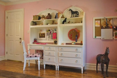 Example of a mid-sized classic girl medium tone wood floor and brown floor kids' room design in New York with pink walls