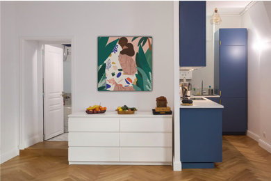 Idées déco pour une cuisine ouverte haussmannienne moderne en L avec un évier intégré, des portes de placard bleues, un plan de travail en stratifié, une crédence blanche, un sol en bois brun et un plan de travail blanc.