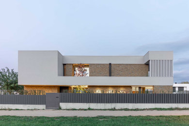 Modelo de fachada de casa blanca y blanca moderna grande de tres plantas con revestimiento de piedra y tejado plano