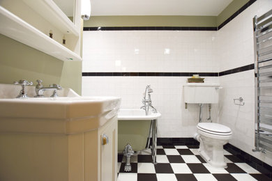 Kleines Klassisches Badezimmer En Suite mit Kassettenfronten, weißen Schränken, Löwenfuß-Badewanne, Wandtoilette mit Spülkasten, weißen Fliesen, grüner Wandfarbe, Schiebetür-Duschabtrennung, Einzelwaschbecken und eingebautem Waschtisch in London